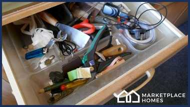 An extremely messy drawer fool of pens, tools, and other miscellaneous unorganized items.