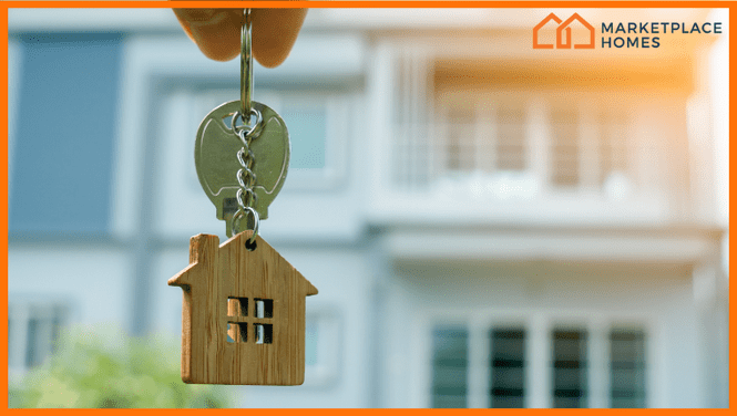 picture of a hand holding a key in front of a home.